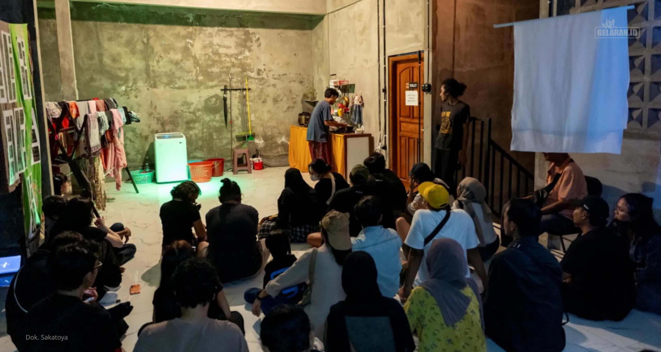Ahmad Abdushomad mengerjakan pekerjaan dapur dalam ruang pertunjukan domestik yang disaksikan langsung oleh penonton di Sakatoya Collective Space.