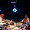 Amalia Rizqi dan Ericha Nurcholifatin melipat pakaian di tengah tumpukan baju dalam pertunjukan Tubuh Domestik: Mengurai Residu di Sakatoya Collective Space.